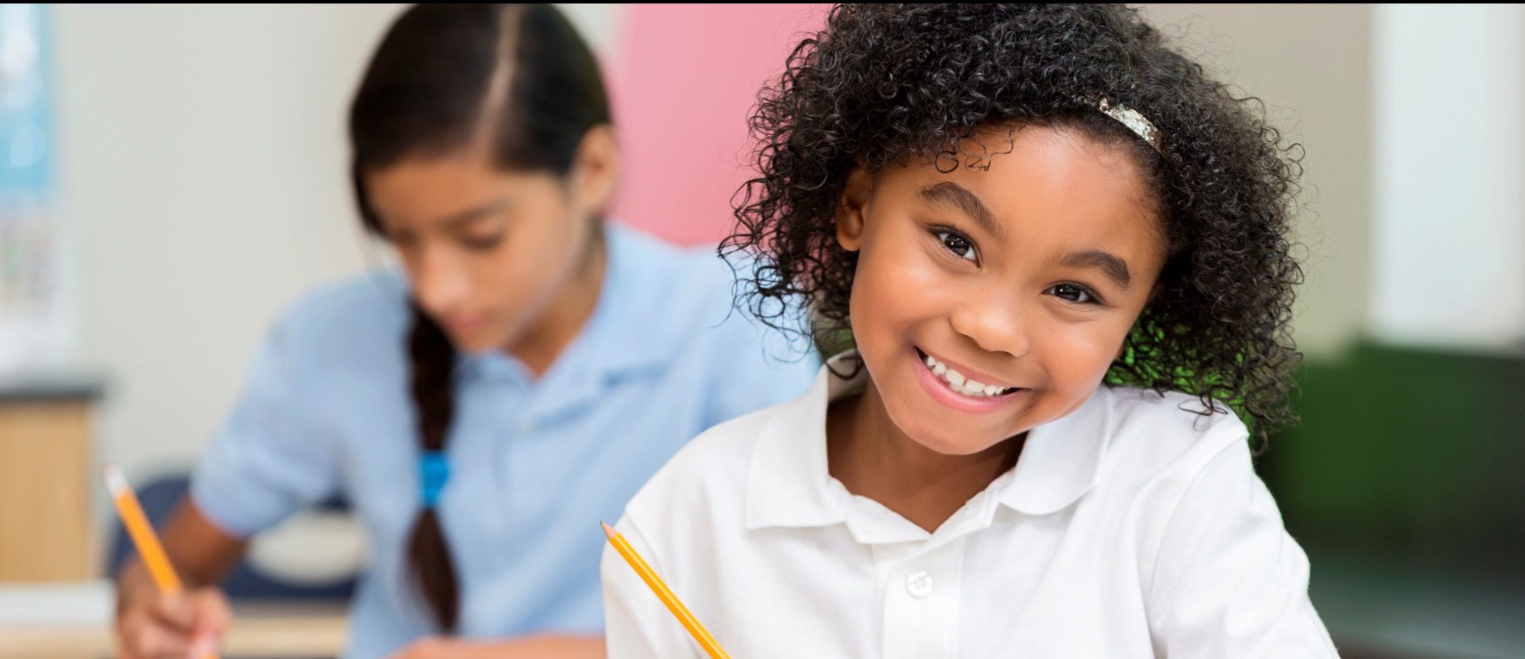 Elementary student smiling at desk.